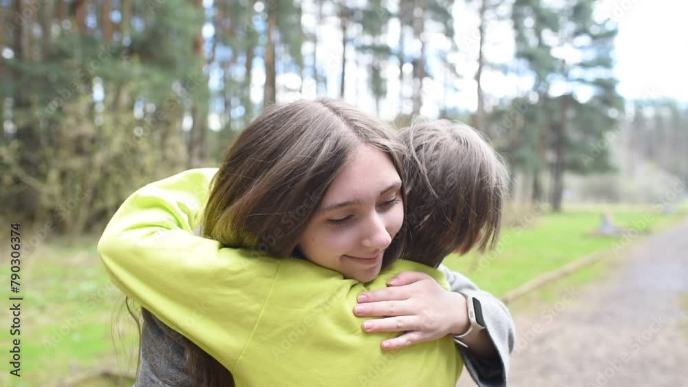 10 year old brother hugs his older sister in the park
