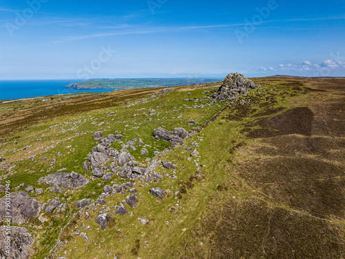 Aerial shot of exposed rocky outcrops surrounded by moorland and farmland with coastline in the distance. Pembrokeshire, Wales