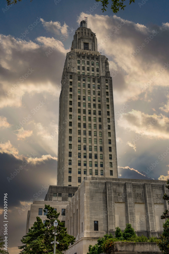 The Louisiana State Capitol building with lush green trees, blue sky and clouds in Baton Rouge Louisiana USA