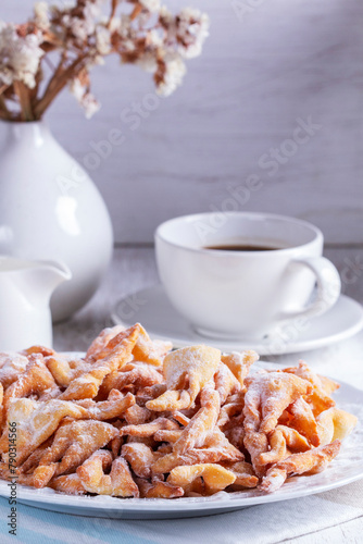 Traditional Maslenitsa dessert angel wings served with coffee on a light background.