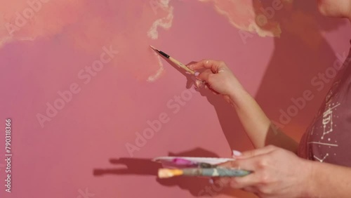 caucasian woman hand painting abstract sunset or sunrise wall artwork with acrylic ink at loft room at home, renovation or wall painting concept