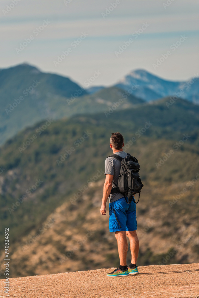 hiker with backpack standing on mountain peak overlooking a stunning mountain range