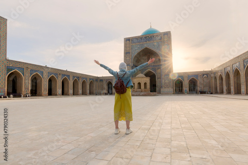 Young tourist with arms up inside the Kalyan Mosque, part of the Po-i-Kalyan complex in Bukhara, Uzbekistan