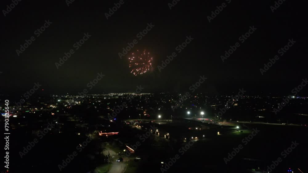 Drone night view of fireworks in dark sky over illuminated city