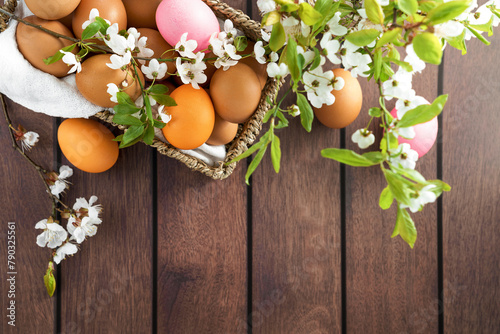 A beautiful bouquet of flowers and colorful Easter eggs displayed in a basket on a rustic wooden table, creating a lovely spring centerpiece © Маргарита Трушина