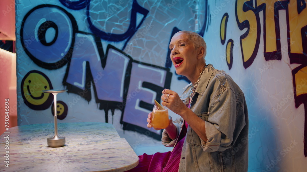 Fototapeta premium Joyful woman singing cafe with cocktail. Carefree trendy senior dancing club