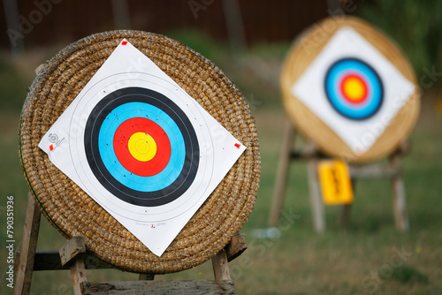 Two archery targets in focus, one close-up and one in the distance on stands.