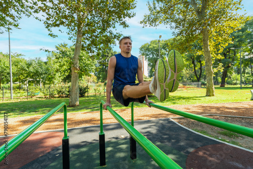 Young guy athlete exercising on sports equipment in the park