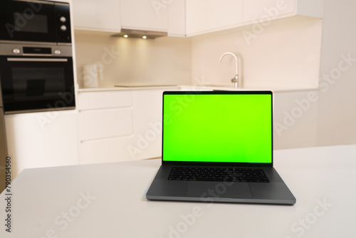 Green screen laptop on white kitchen background stands on white table, screen replacement laptop, home office, work from home