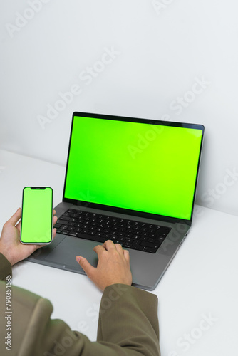 An unrecognisable man is using a laptop while working remotely at home close-up. A manager scrolls on a touchpad and holds a phone while browsing the internet. An employee touches a computer keyboard.