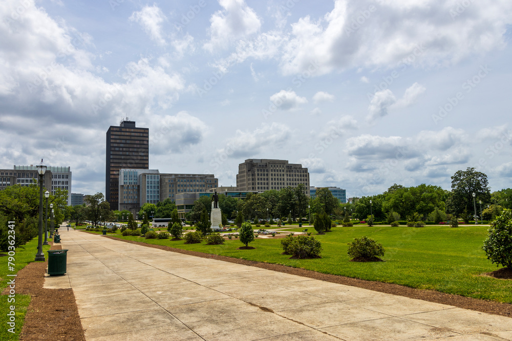a beautiful spring landscape at Capitol Gardens with lush green trees, plants and grass, colorful flowers and office buildings in the skyline at the Louisiana State Capitol In Baton Rouge Louisiana