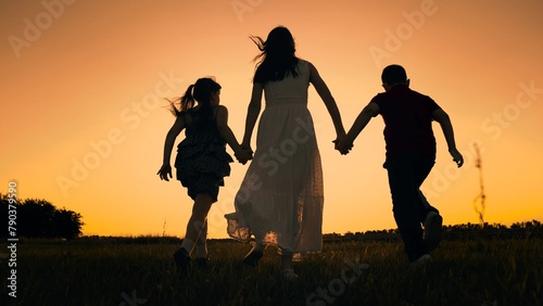 silhouette mother runs into sunset holding her son daughter hand  happy family running  boy girl  interest life  our adventure begins  kids playing meadow  when sun sits background  running playing
