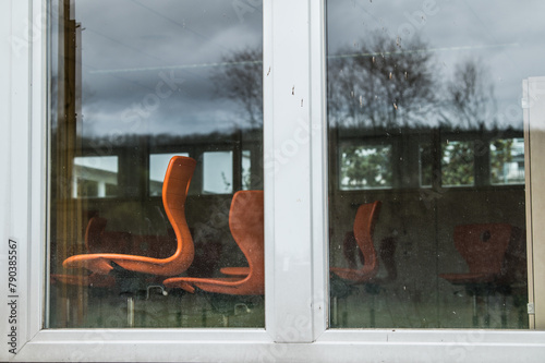 Leere Drehstühle hinter Fenster mit Spiegelung von kahlen Bäumen am Schulzentrum in Neckartenzlingen