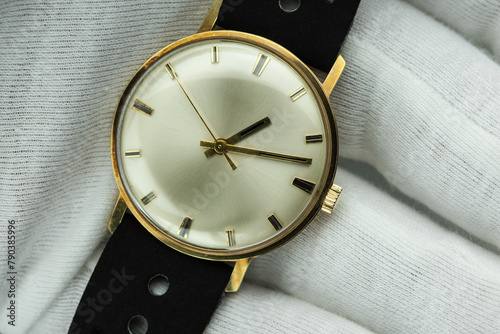 Watchmaker in white gloves proudly presents a handcrafted gold watch from the 1960s - a masterpiece of bygone elegance and precision.