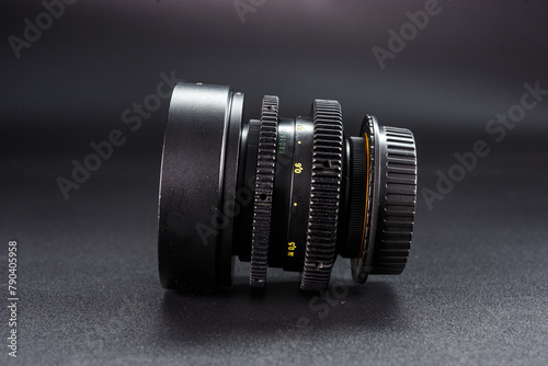 Antique optical camera lens with visible focus scales, depth of field controls, collector's vintage photography equipment, profile shot with dark gradient backdrop