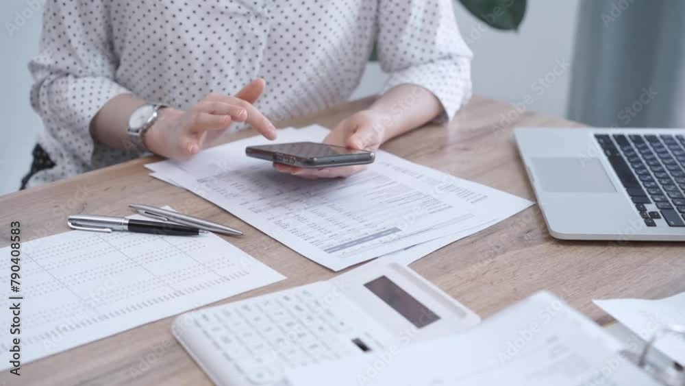 Close-up of an adult's hands with smartphone, calculator, and documents on a desk in office. Bookkeeping, finance, audit and taxes. Business concept Close-up of an adult's hands with smartphone, calculator, and documents on a desk in office. Bookkeeping, finance, audit and taxes. Business concept