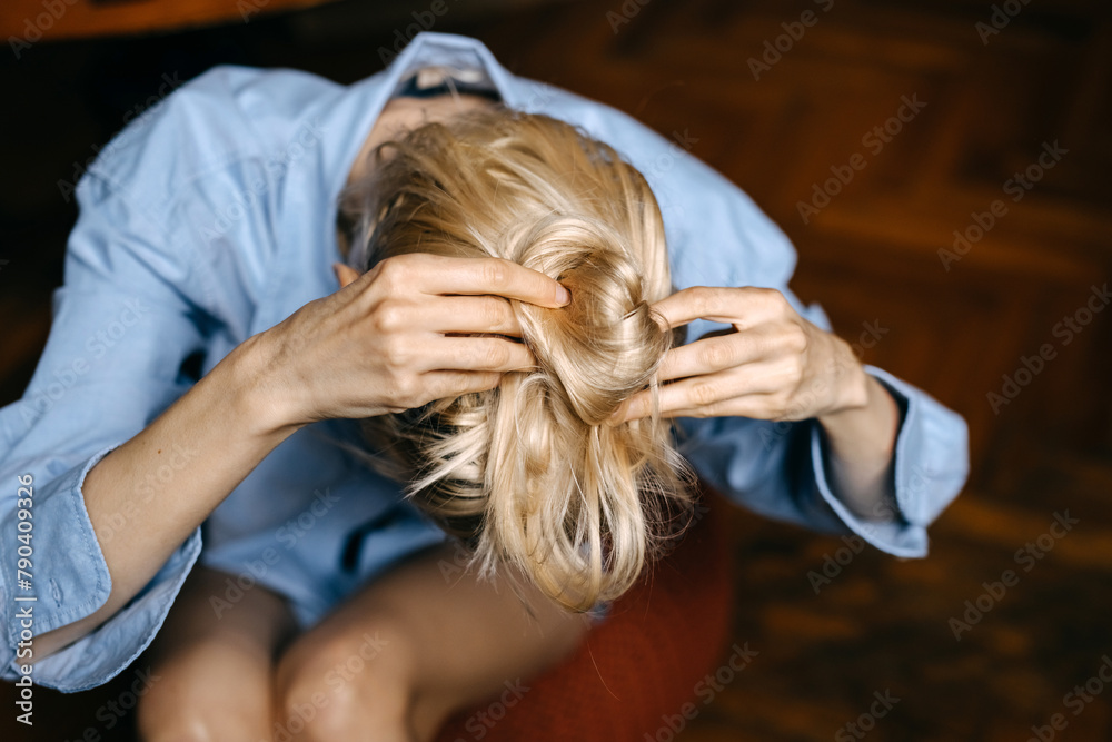 Fototapeta premium Closeup of a blonde woman making a hair bun.