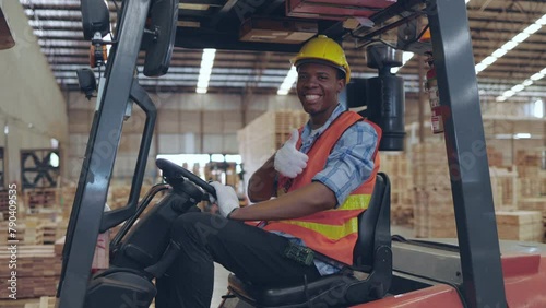 A forklift driver at a lumber warehouse displays a positive attitude with a thumbs-up gesture.