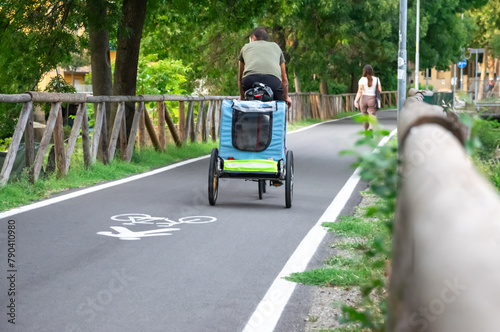 Parent taking bike ride with stroller to his child in park with wooden fence