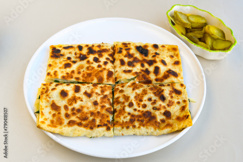 Freshly baked appetizing Turkish tortillas -Gozleme with spinach, cheese  on a wooden board. Shallow depth of  field. Handmade Turkish traditional pastries. Otlu peynirli ispanakli gozleme. photo