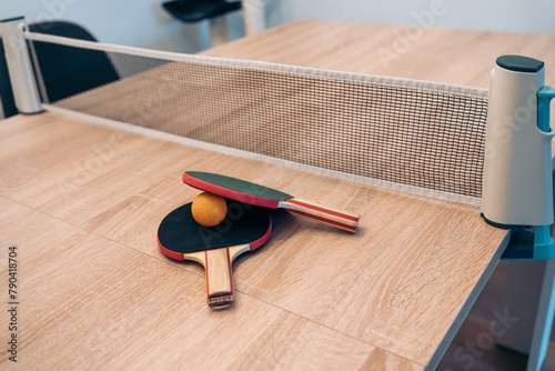 Pingpong paddles and net on indoor table at home. Portable mini pingpong set installed on a wooden table at home.