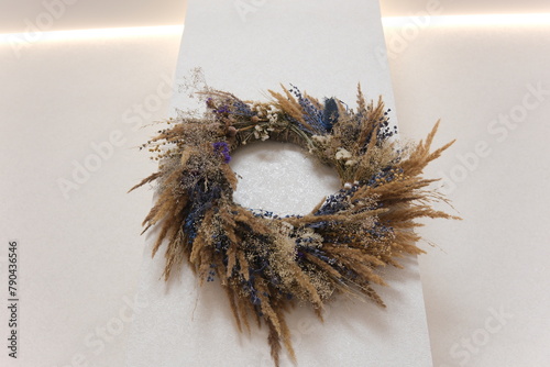 Poppy spikelets of wheat predominance of blue dried herbs in beautiful decoration on wall we will weave wreath With love, handmade art Dried wildflowers create the atmosphere. wreath of dried herbs