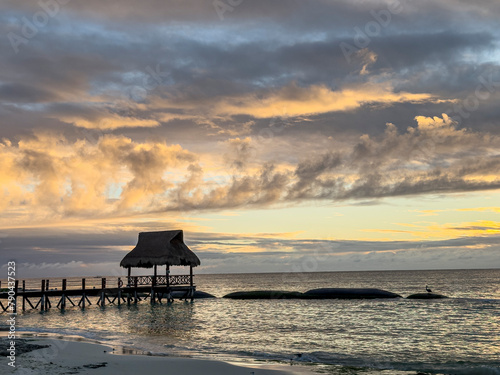 sunrise over a covered dock along the beach