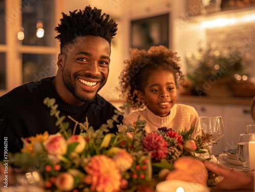 A man and a young girl are smiling at the camera while sitting at a table with a beautiful floral centerpiece. Scene is warm and inviting  as the family is enjoying a meal together