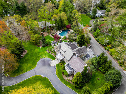 This drone-captured image offers a stunning overview of a prosperous neighborhood in Millburn, NJ, where elegant homes are surrounded by well-kept gardens and private pools, signifying a high standard