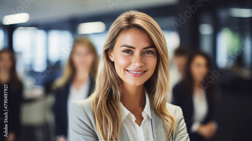 The smiling female CEO of a small start up company with her employees standing behind her.