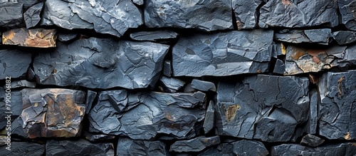 Close-up view of a solid stone wall set against a deep black background, showcasing rugged texture and natural formation