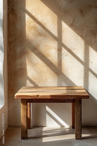 Wooden table with sunlight shadows on beige background for product display.