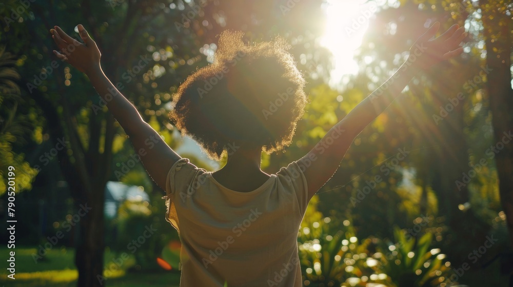 Black woman raising her arms in the air, surrounded by trees