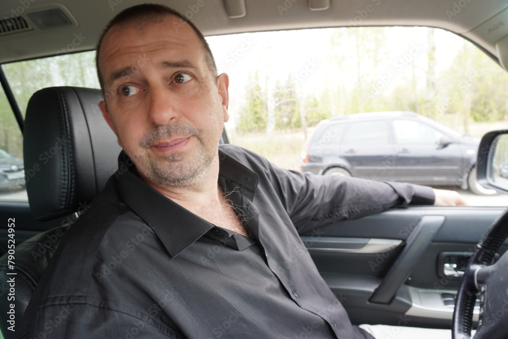 Man 50 years old in a black shirt driving a car Man 50 years old in a black shirt driving a car