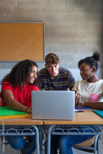 Multiracial group of high school students doing homework research together using laptop in class. Vertical image.