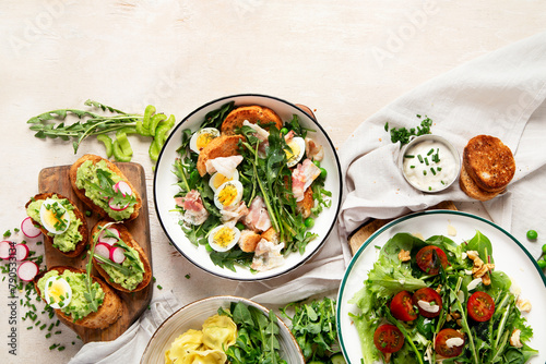 Spring fresh food with green leaf. Salads with strawberries, bacon and ravioli on light wooden background