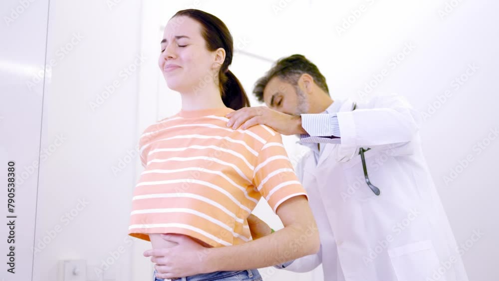 Woman complaining about back pain in a clinic Woman complaining about back pain in a clinic