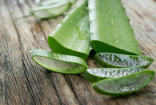 Aloe vera pieces on wooden background, fresh aloe vera, green herbal plants. photo