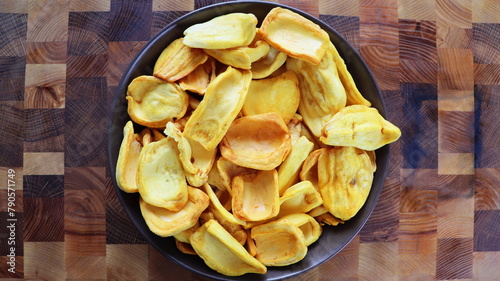 Organic dried jackfruit chips from tropical island Ceylon. Fruits chips for vegan with antioxidant, vitamin in white plate on gray background. Top view