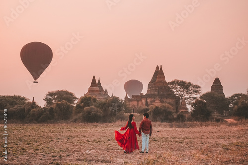 Couple stands watching balloons float at Bagan temple in Myanmar archaeological zone in the morning.
