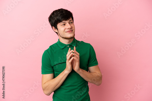 Young Russian man isolated on pink background scheming something