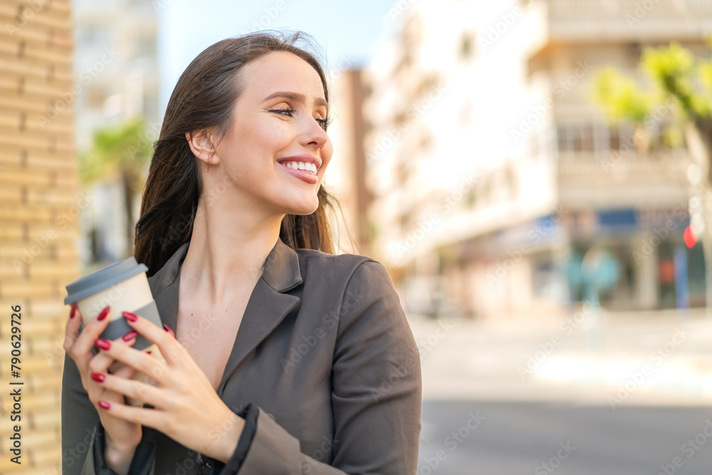 Young woman at outdoors holding a take away coffee Young woman at outdoors holding a take away coffee