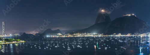 Panoramic Night View of Sailboats and City Lights by the Sea