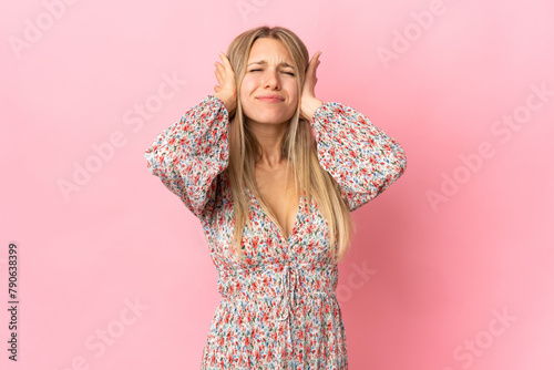 Young blonde woman isolated on pink background frustrated and covering ears