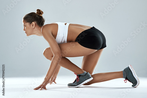 Athlete, woman and ready to race in studio as runner for fitness, training and exercise for sports. Healthy, female person and active with sportswear sprint for cardio, strong and natural muscles