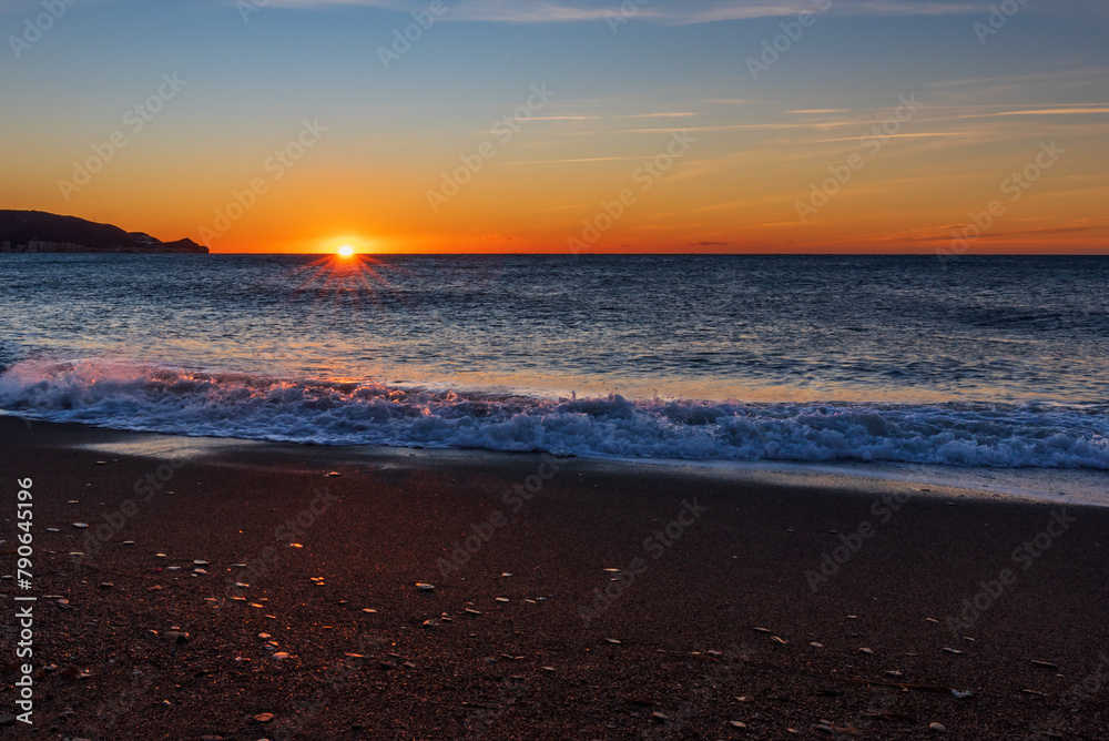 Poniente Beach in Motril, Granada, with the sun rising at dawn over the horizon of the Mediterranean Sea, tropical coast