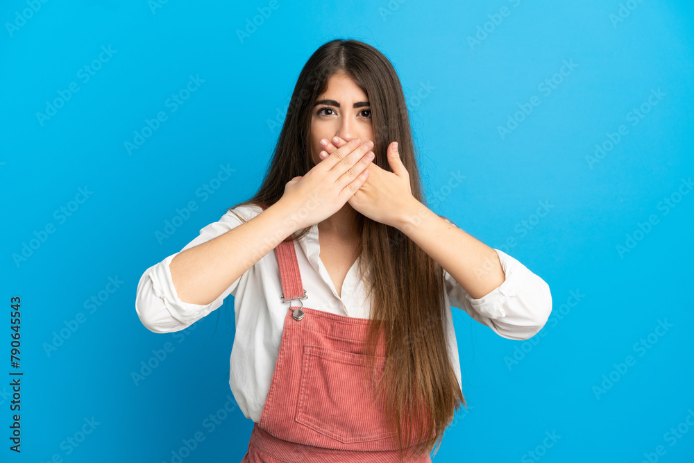 Young caucasian woman isolated on blue background covering mouth with hands Young caucasian woman isolated on blue background covering mouth with hands