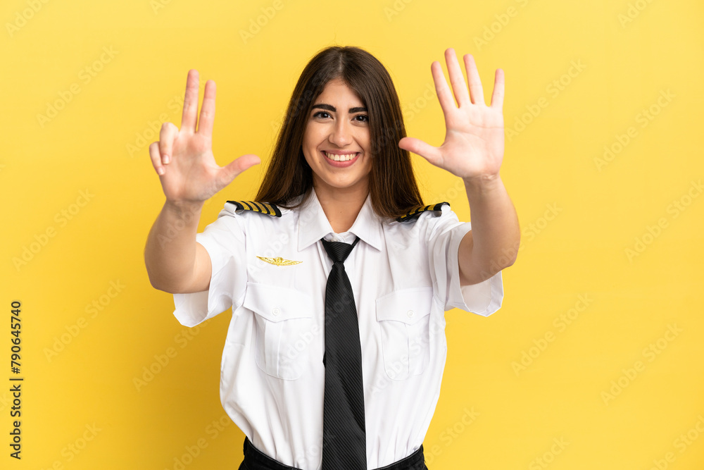 Airplane pilot isolated on yellow background counting eight with fingers