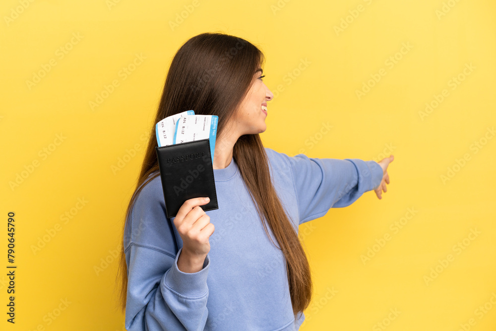 Naklejka premium Young caucasian woman holding a passport isolated on yellow background extending hands to the side for inviting to come