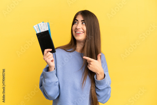 Young caucasian woman holding a passport isolated on yellow background intending to realizes the solution while lifting a finger up